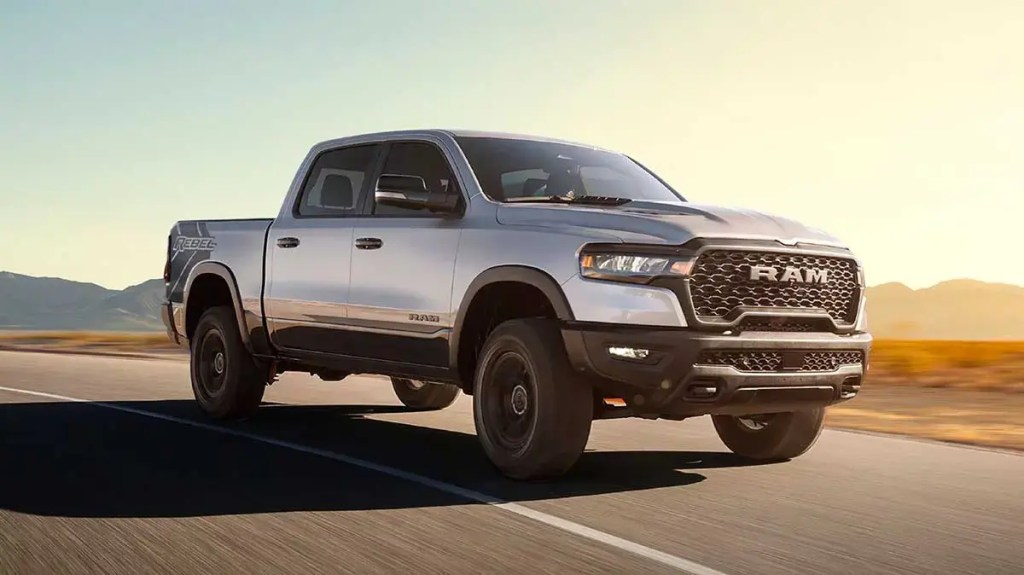 Pickup RAM 1500 en movimiento sobre un camino, con un paisaje montañoso de fondo y luz del sol al atardecer.