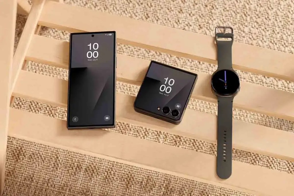 Un smartphone Galaxy Z Fold7, un Galaxy Z Flip7 y un reloj inteligente sobre una mesa de madera con un fondo de textil claro.