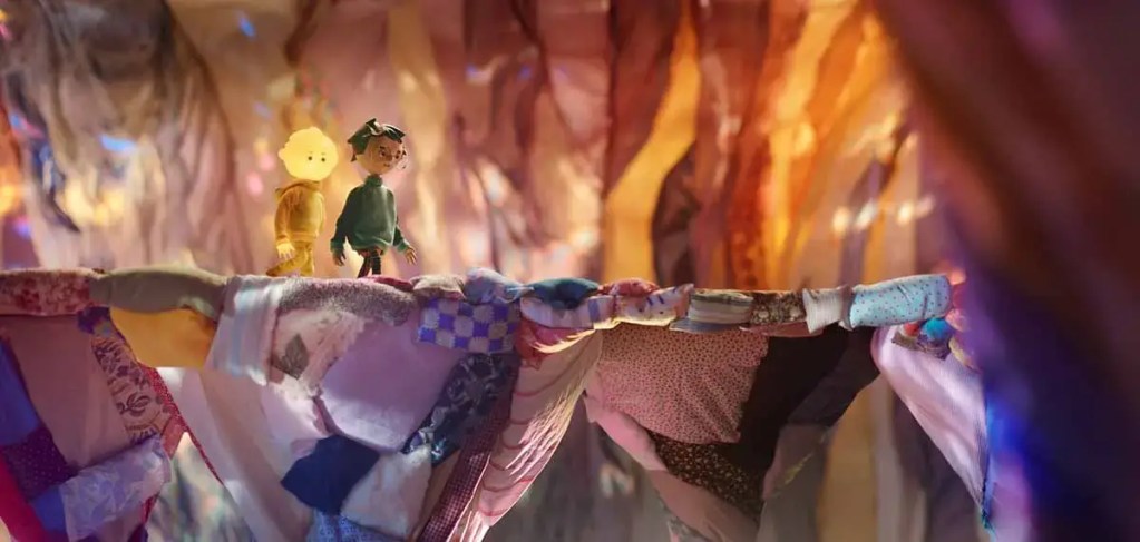 Marionetas de dos niños deambulando en un paisaje colorido hecho de telas en la película de animación 'Tony, Shelly y la Linterna Mágica'.