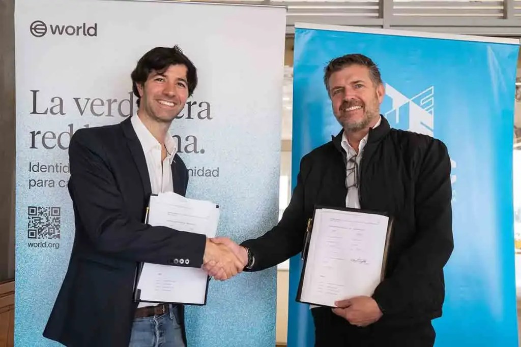 Dos hombres estrechando manos frente a banners que representan una colaboración entre la Universidad de Ingeniería y Tecnología (UTEC) y World. Uno de los hombres sostiene documentos y ambos muestran expresiones de satisfacción.