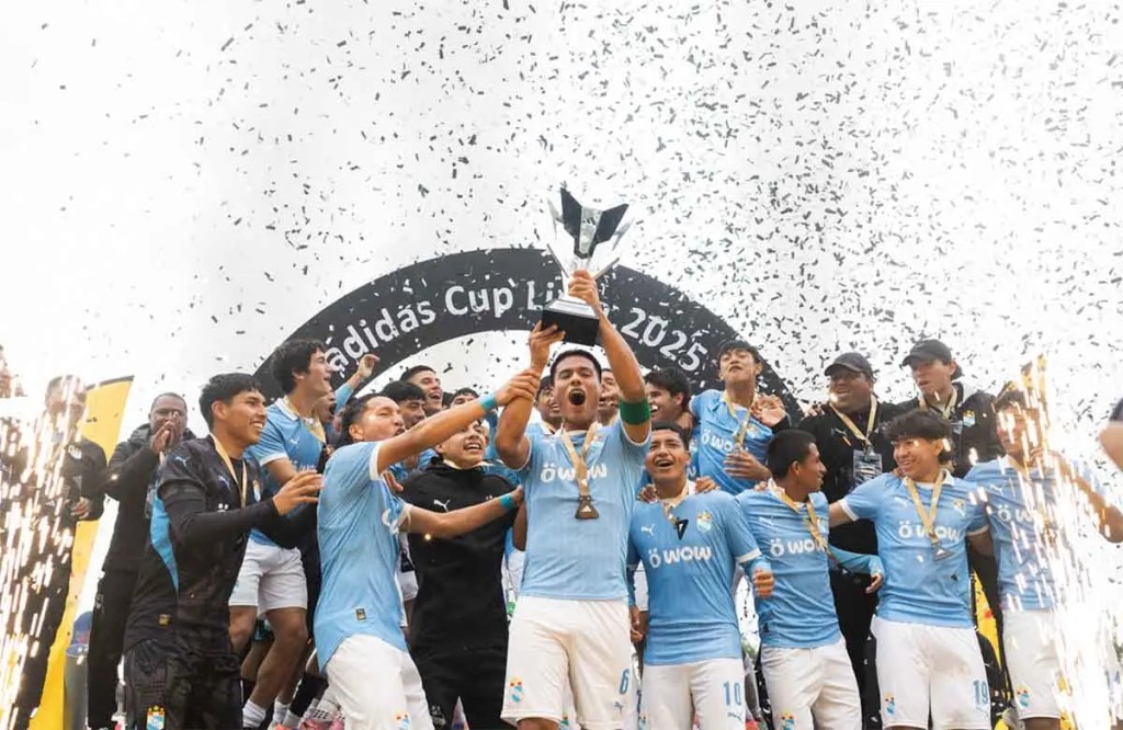 Jugadores de Sporting Cristal celebran su victoria en la adidas Cup Lima 2025, levantando el trofeo entre confeti y fuegos artificiales.
