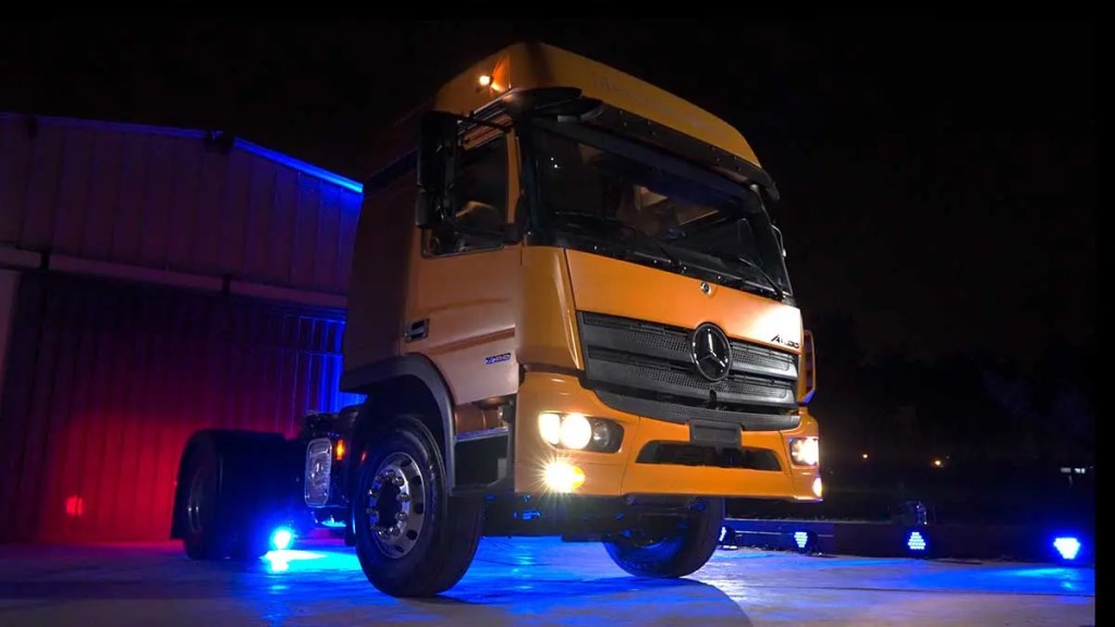 Camión Mercedes-Benz Atego 1933 4x2 iluminado en un evento nocturno, mostrando su diseño robusto y moderno, con luces resaltando su estructura.