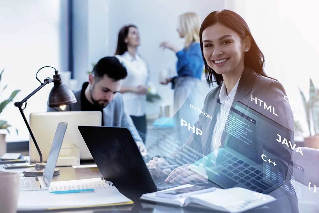 Mujer sonriente trabajando en una laptop en un entorno de oficina moderna, con gráficos y lenguajes de programación superpuestos en la imagen.