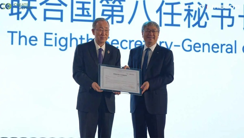 Ban Ki-moon y un representante de OMODA & JAECOO sosteniendo un certificado en un evento de sostenibilidad en Wuhu, China.