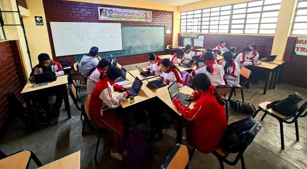 Estudiantes de secundaria en un aula trabajando con computadoras portátiles, participan en un programa de capacitación en inteligencia artificial y herramientas generativas.