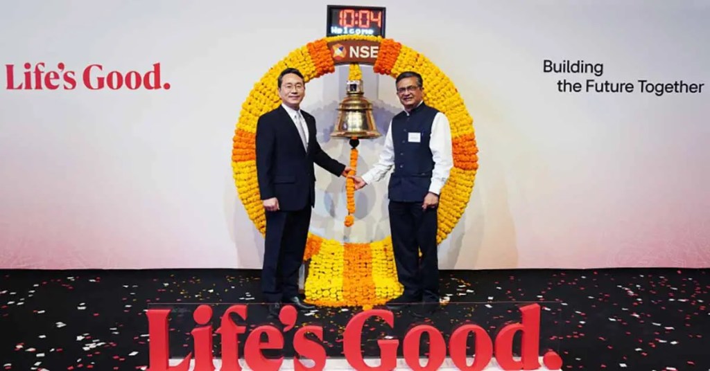 Dos ejecutivos de LG Electronics celebran el anuncio de la inclusión de LG Electronics India Limited en la Bolsa Nacional de Valores de India, junto a un gong ceremonial decorado con flores.