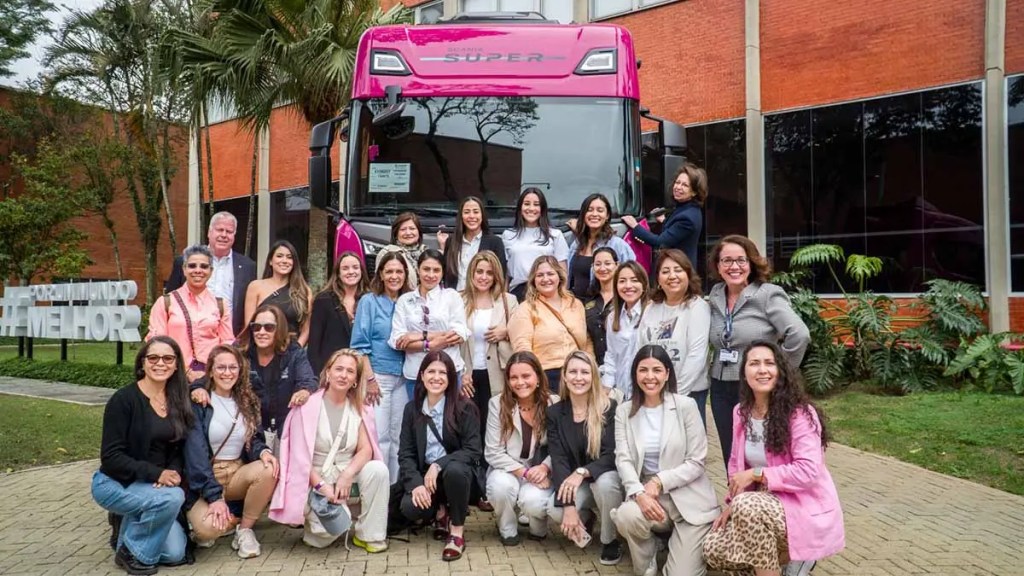 Un grupo de más de 20 mujeres líderes del transporte latinoamericano se reúne frente a un autobús de color rosa durante el evento Queen on the Road en São Paulo, Brasil.