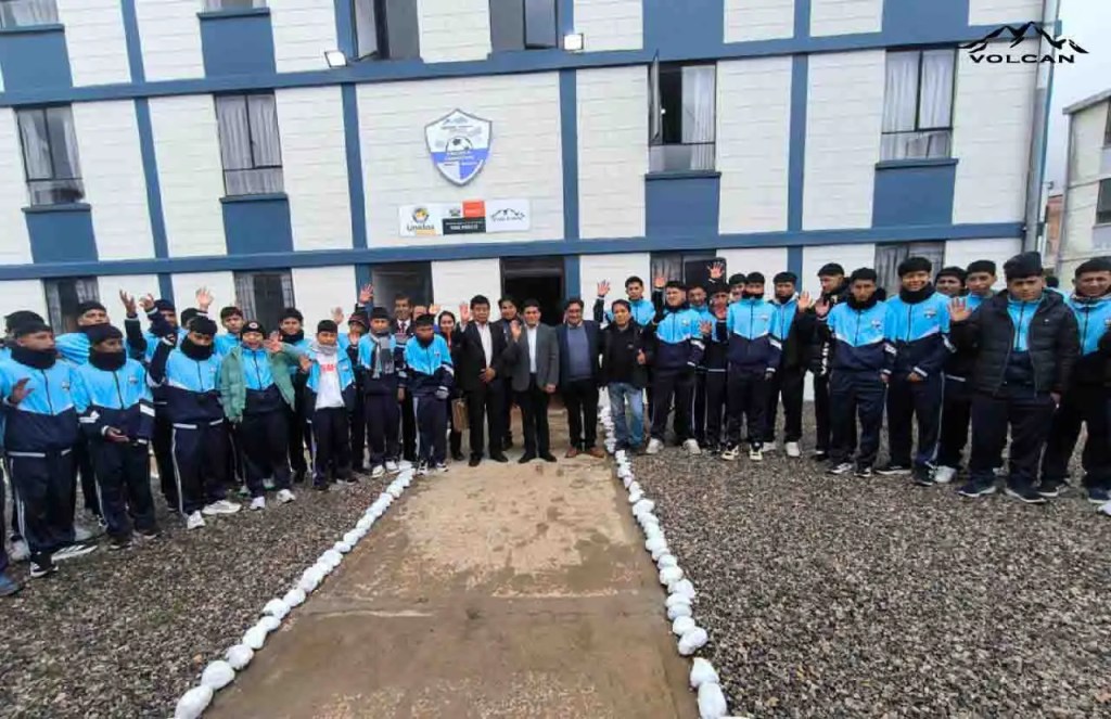 Grupo de jóvenes atletas con ropa de entrenamiento frente a un edificio, junto a funcionarios de Volcan y el Gobierno Regional de Pasco, durante la firma de un convenio para un Centro Deportivo en Pasco.