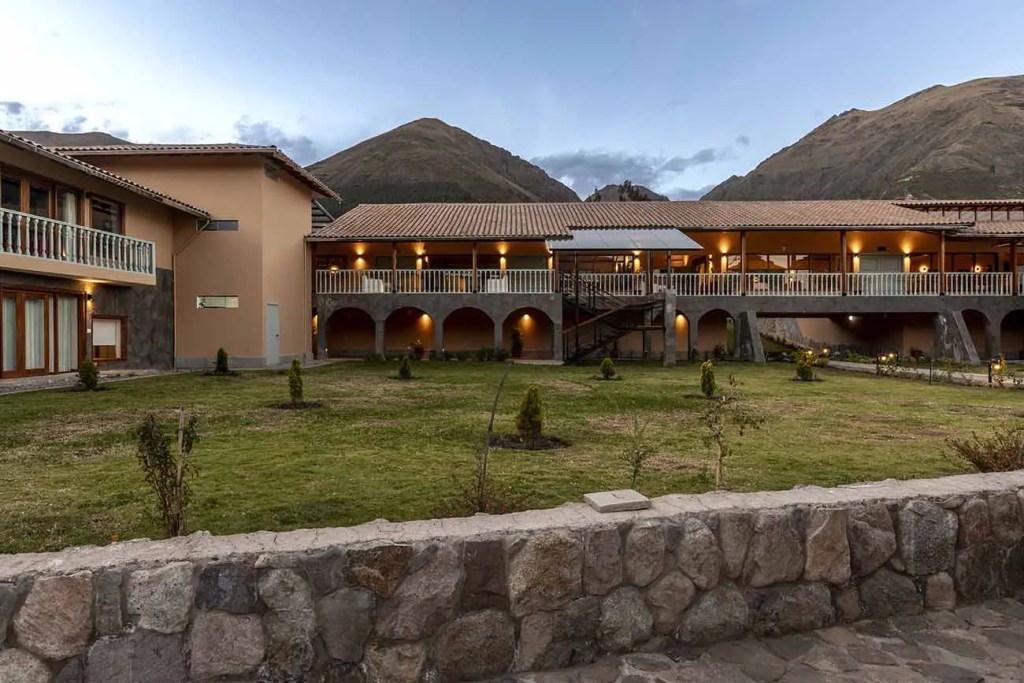 Vista del exterior de Casa Eva Hotel Boutique, ubicado en el Valle Sagrado de los Incas, con jardines verdes y montañas al fondo.