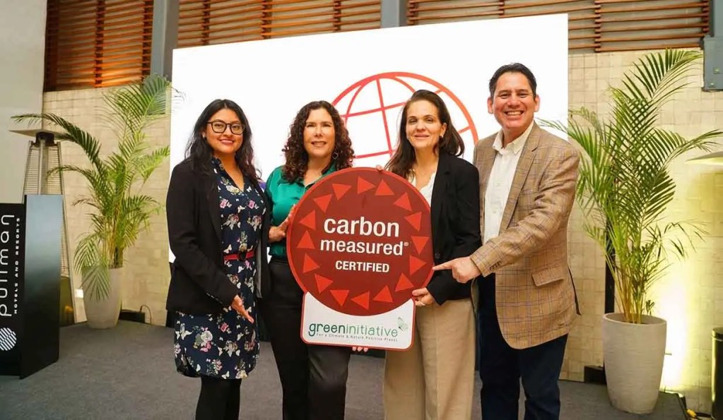 Grupo de cuatro personas sosteniendo un letrero que dice 'carbon measured certified' en un evento en el Hotel Pullman San Isidro.