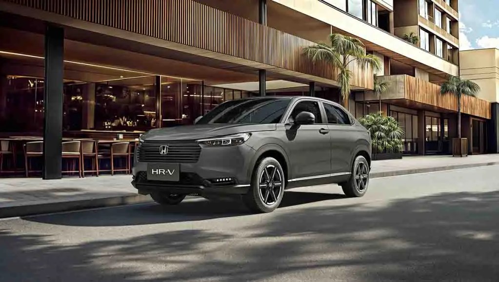 Vista frontal de la nueva Honda HR-V 2026, una SUV elegante y sofisticada, estacionada frente a un edificio moderno con elementos de diseño contemporáneo y plantas decorativas.
