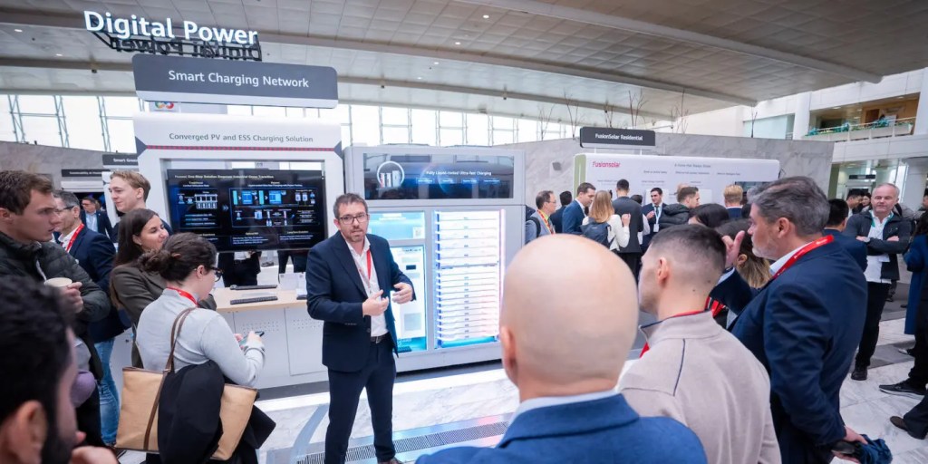 Un grupo de personas en un evento de Huawei Digital Power, observando soluciones de energía solar y carga de vehículos eléctricos.