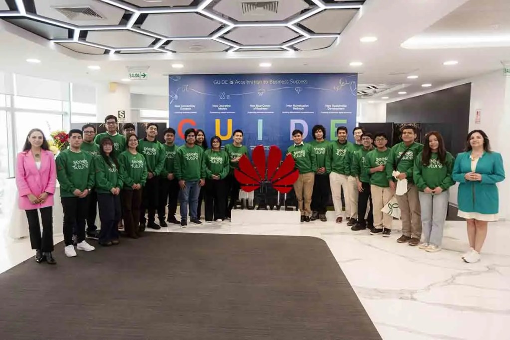 Grupo de estudiantes participantes del programa Semillas para el Futuro de Huawei, vestidos con sudaderas verdes, posan para una foto grupal frente a un fondo que presenta el logo de Huawei y el lema del programa.