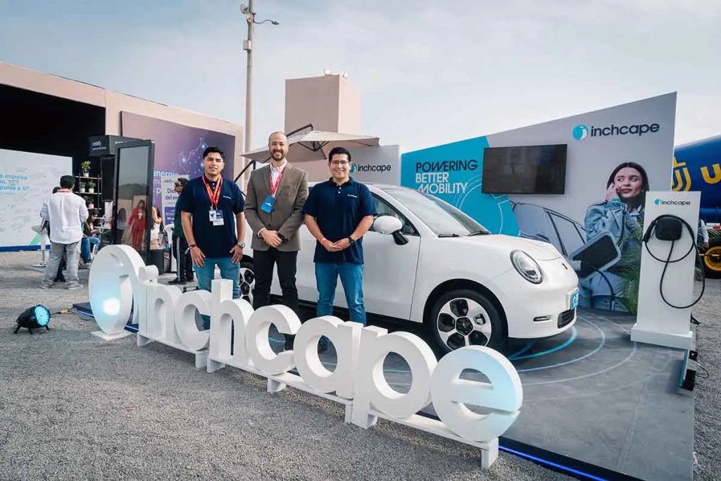 Stand de Inchcape en la Cumbre Perú Sostenible 2025, con un vehículo eléctrico JAC e-30x y tres representantes de la empresa posando frente a él.