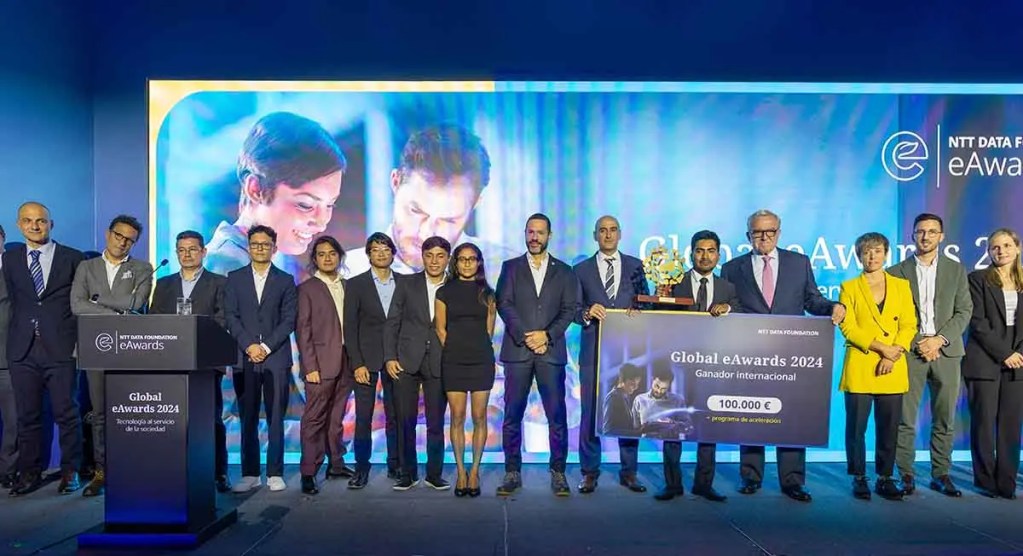 Grupo de finalistas y organizadores posando en el evento de los Global eAwards 2024, sosteniendo un trofeo y un cheque por 100.000 € en una ceremonia de premiación.