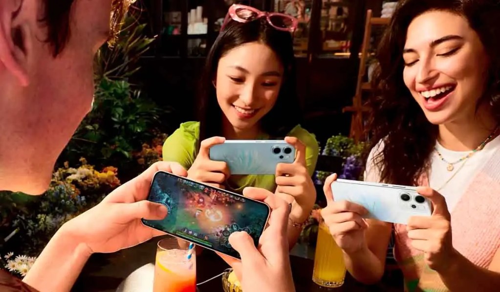 Tres personas interactuando con smartphones en un entorno social, disfrutando de un momento juntos.