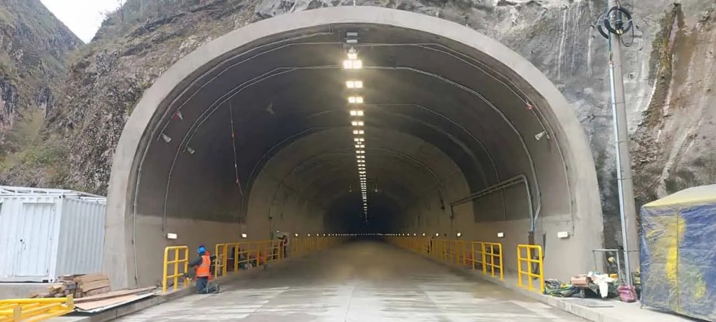 Vista del interior del túnel Ollachea, mostrando la iluminación y las obras de infraestructura, con paredes de roca y maquinaria en los costados.