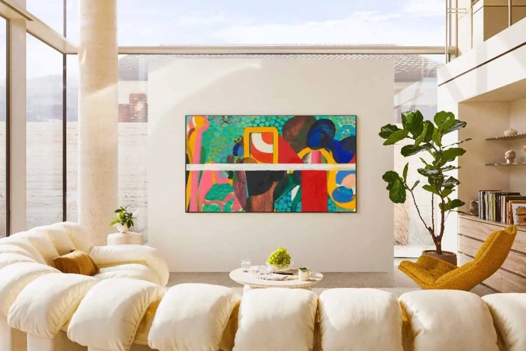 Sala moderna con un televisor Samsung en la pared, mostrando una obra de arte colorida. Sofás de diseño contemporáneo y una planta decorativa complementan el ambiente.