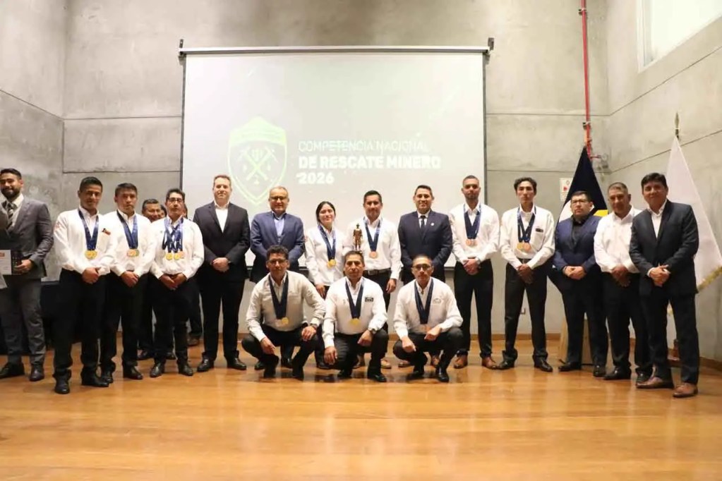 Grupo de participantes de la Competencia Nacional de Rescate Minero 2026, con medallas y trofeos en un evento en interiores, con una presentación de fondo.