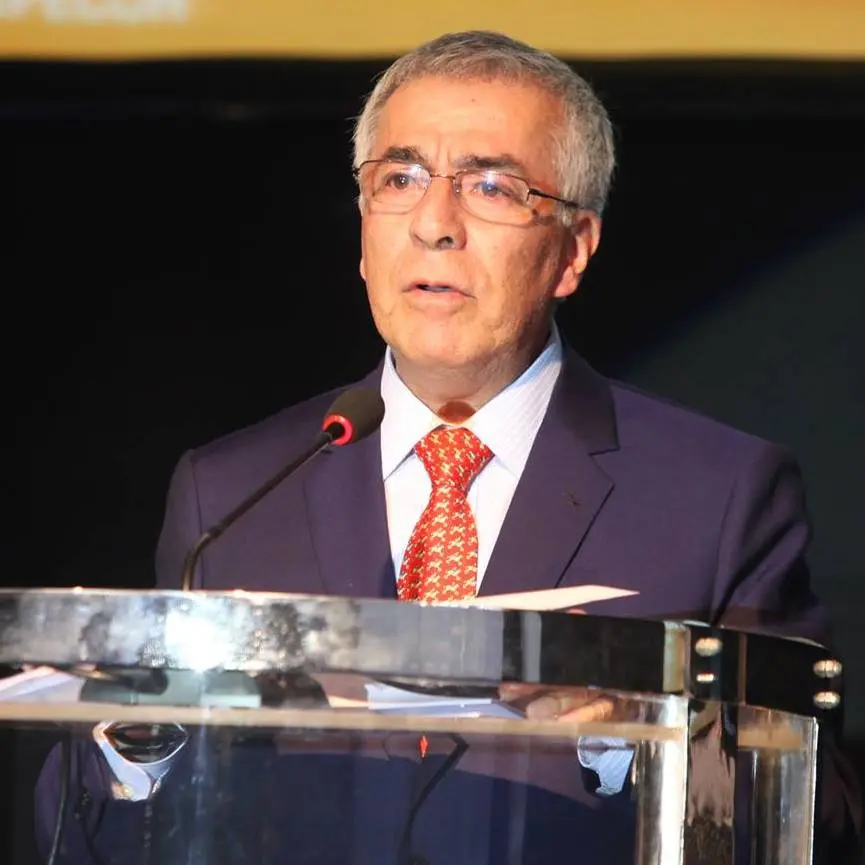 El gran maestro peruano Ángel Acevedo dando un discurso, vestido con un traje oscuro y una corbata roja, mientras se presenta en un evento relacionado con el ajedrez.