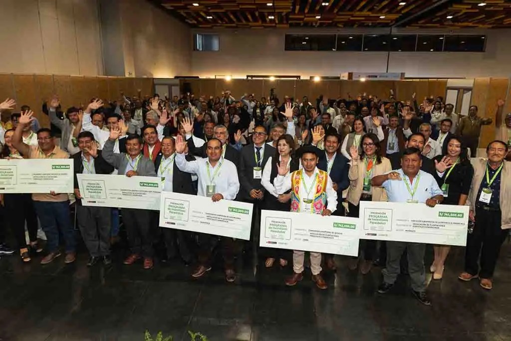 Grupo de personas en un evento celebrando la entrega de cheques del Programa de Incentivos Forestales 2025, con sonrisas y saludos, en un ambiente de camaradería.