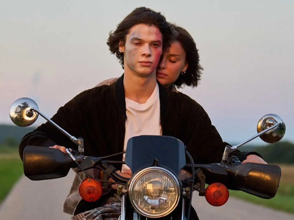 Pareja joven montando una motocicleta al atardecer, con una sensación de intimidad.