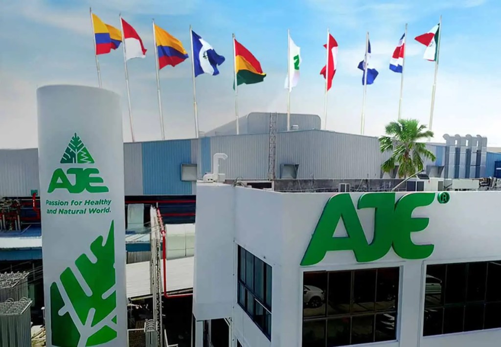 Edificio de AJE con el logo visible, rodeado de banderas de varios países, en un día soleado.