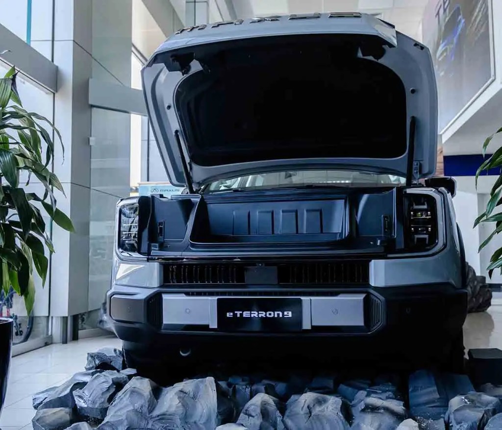 Vista frontal de un vehículo eléctrico eTerron 9 con el capó abierto, exhibido en un showroom.