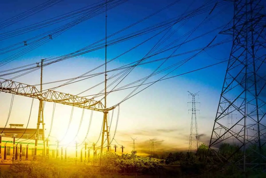 Estructuras de líneas eléctricas al atardecer, con cielo azul y dorado.