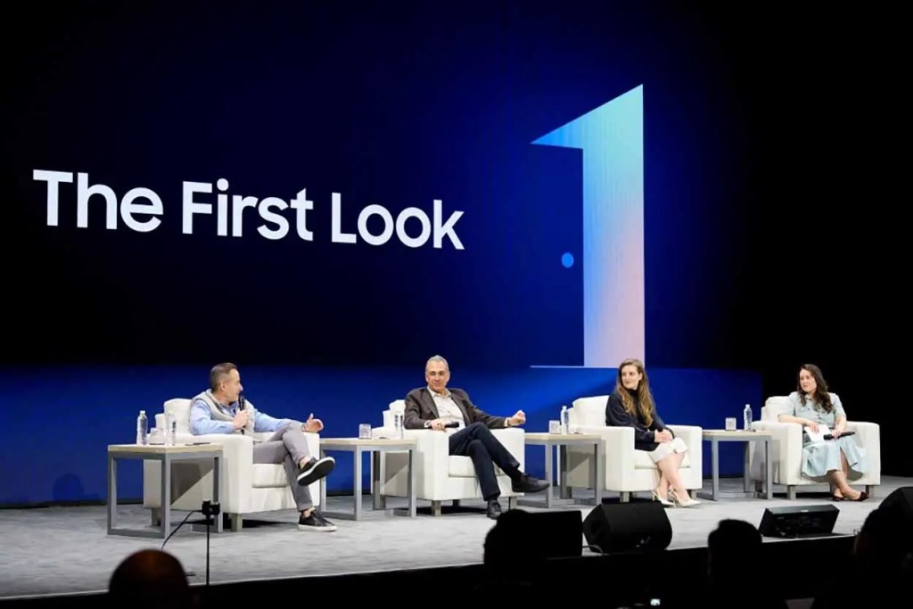 Panel de discusión en el Consumer Electronics Show (CES) 2026, con cuatro participantes sentados en sofás frente a una pantalla que dice 'The First Look'.