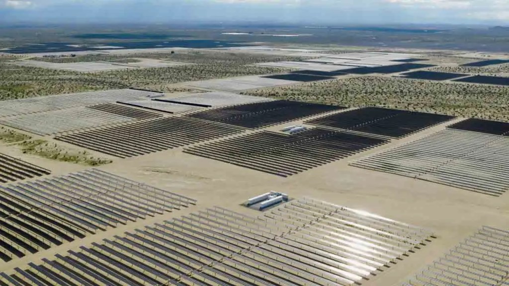 Vista aérea de un gran campo solar con filas de paneles solares dispuestos en un paisaje árido.
