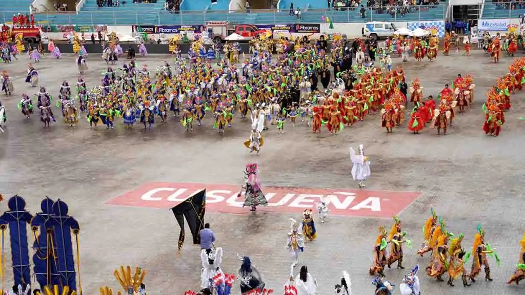Desfile festivo en Cusco con bailarines vestidos en trajes coloridos, representando diferentes tradiciones culturales, en un ambiente de celebración.