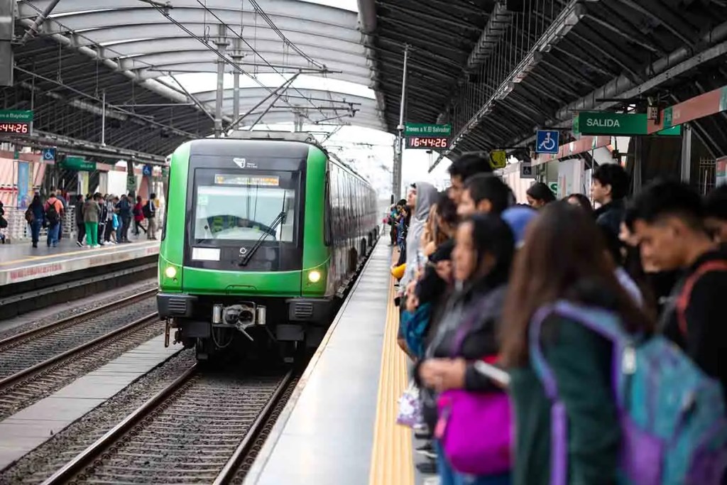 Tren de cercanías verde llegando a una estación con pasajeros esperando en el andén.