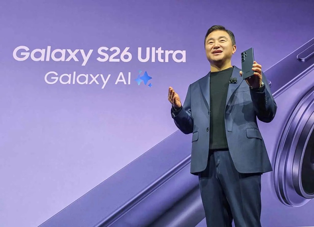 Presentador mostrando el Galaxy S26 Ultra en un evento, con un fondo que dice 'Galaxy AI'.