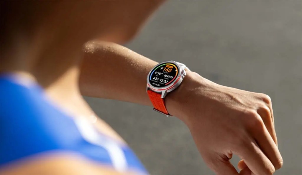 Reloj inteligente deportivo en la muñeca de una persona, mostrando estadísticas de rendimiento y ritmo.