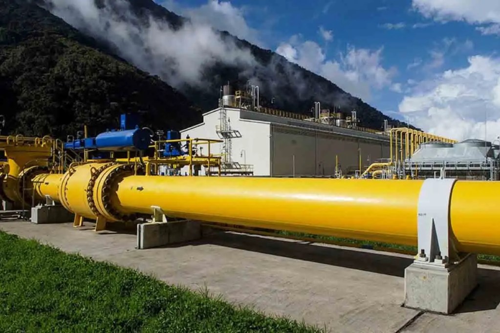 Instalación industrial de tuberías amarillas en un paisaje montañoso con un edificio y cielos despejados.