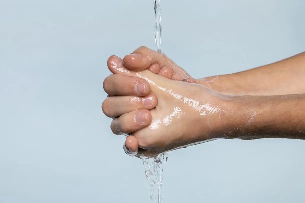 Manos de una persona lavándose con agua, mostrando el proceso de limpieza.