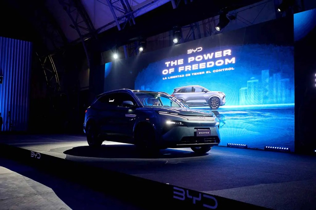 Un vehículo SUV de la marca BYD en un evento de presentación, con un gran fondo que dice 'THE POWER OF FREEDOM' y luces de escenario.