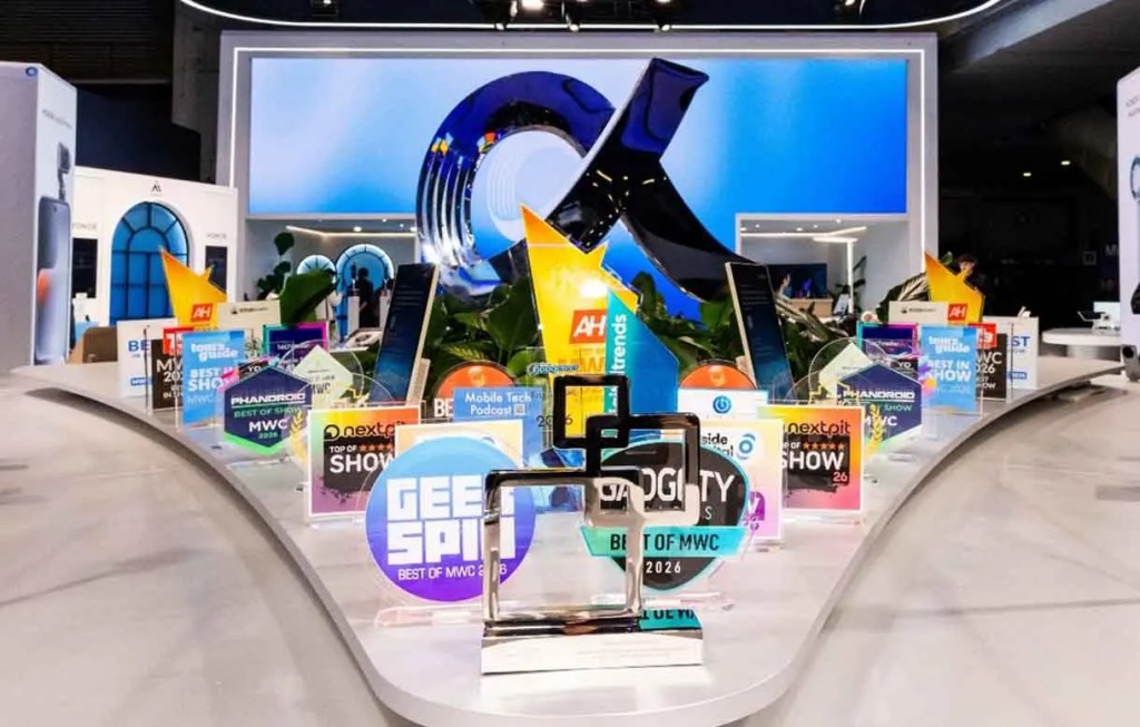 Exhibición de premios y reconocimientos en un evento, con trofeos y placas de varios colores en una mesa decorativa.