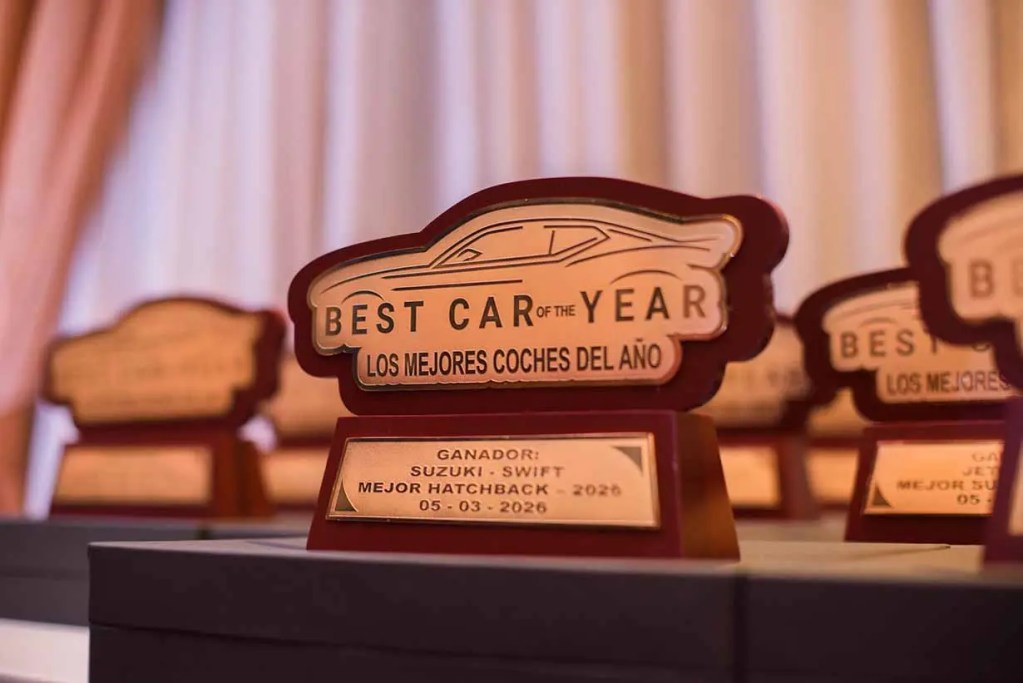 Trofeo que celebra el 'Mejor Coche del Año 2026' para el Suzuki Swift en la categoría de Mejor Hatchback, presentado en un evento.