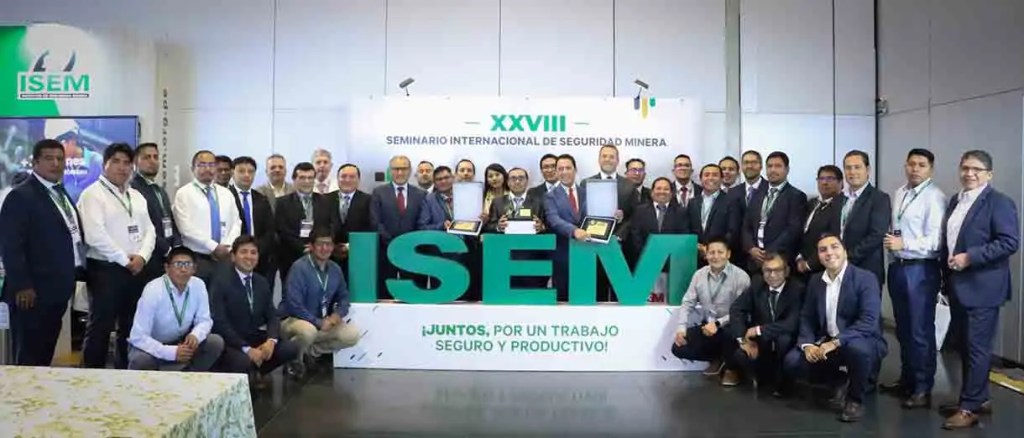 Grupo de participantes en el Seminario Internacional de Seguridad Minera, posando frente a un fondo con el logo ISEM y un mensaje sobre trabajo seguro y productivo.