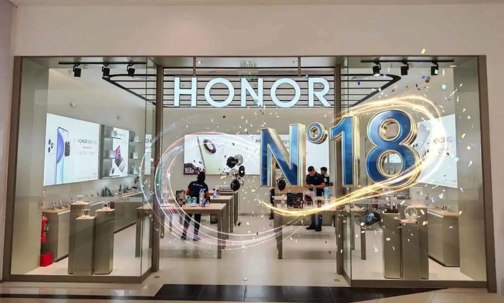Fachada de la tienda HONOR con el letrero 'N°18' y decoraciones festivas, mostrando productos electrónicos en exhibición.