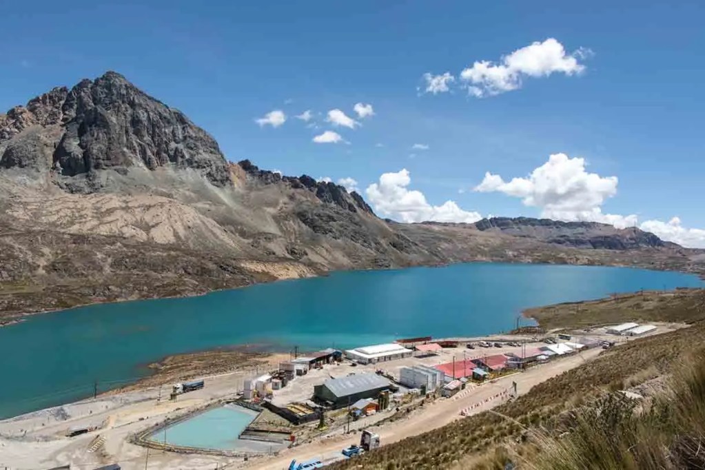 Vista panorámica de un lago en un entorno montañoso, con edificios y estructuras en la orilla.