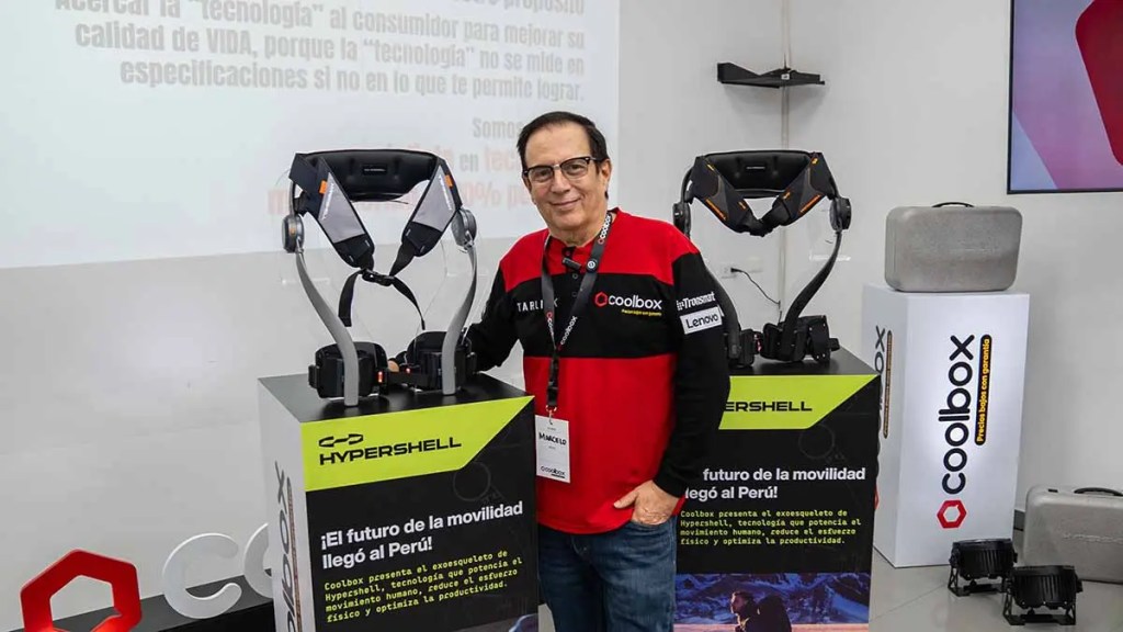 Persona posando junto a un exoesqueleto llamado Hypershell en un evento de presentación de tecnología en Perú.