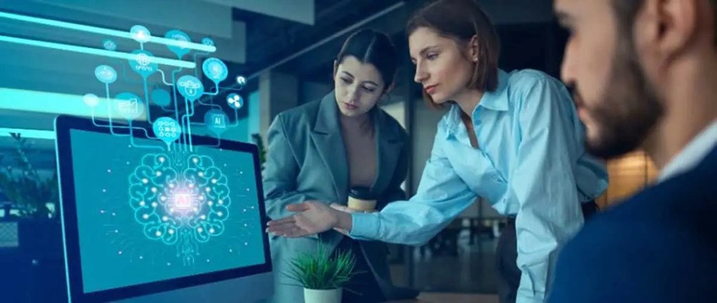 Tres personas discutiendo sobre inteligencia artificial frente a una computadora, con gráficos digitales en pantalla.