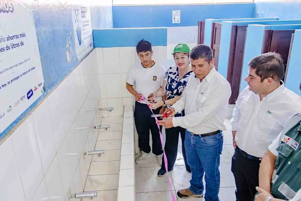 Inauguración de un baño escolar, con varias personas presentes y un grifo visible.