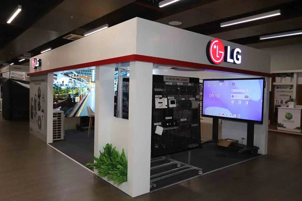 Mostrador de exhibición de LG con una pantalla grande, equipos electrónicos y decoración de plantas.