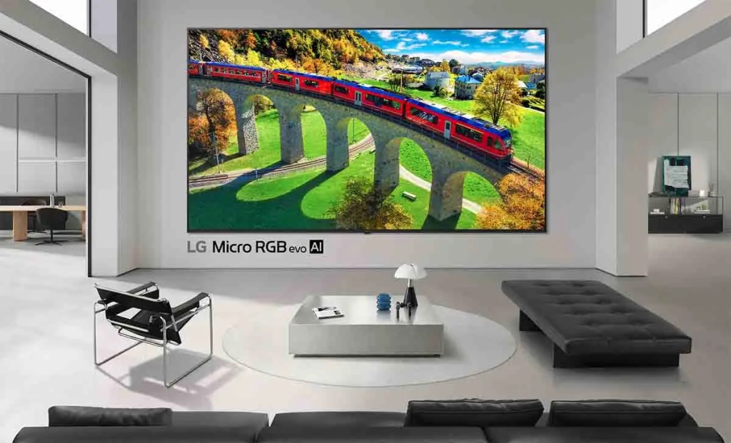 Sala moderna con un televisor LG Micro RGB evo AI mostrando un tren rojo cruzando un puente en un paisaje otoñal.