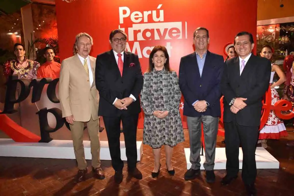Grupo de cinco personas posando frente a un fondo con el texto 'Perú Travel Mart', durante un evento promocional.