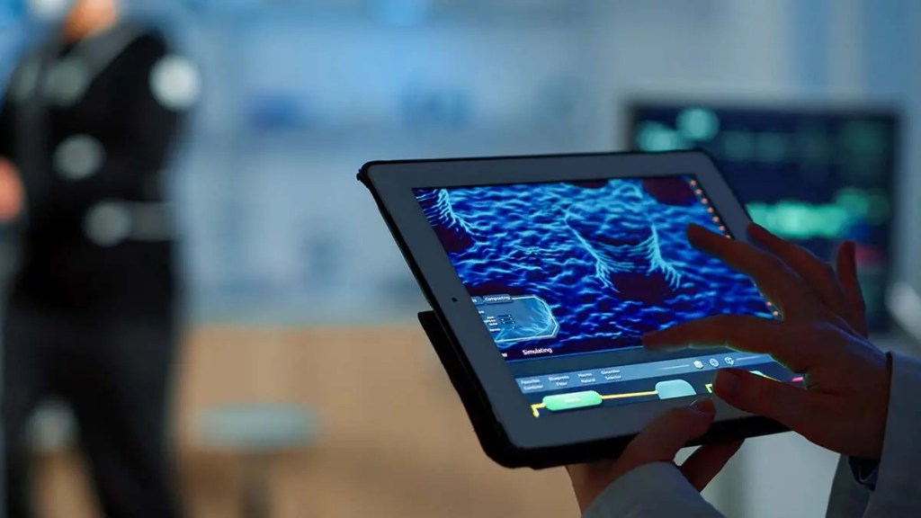 Una persona sosteniendo una tableta que muestra gráficos de simulación en un entorno de laboratorio.